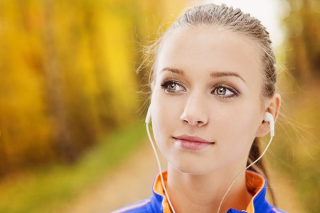 Sporty and active woman runner is listening to music before outdoor exerciseの写真素材