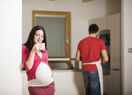 Pregnant woman and happy man in the houseの写真素材