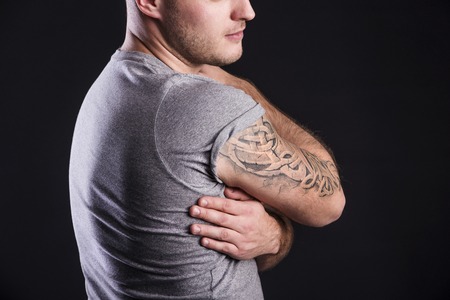 Handsome young man with tattoo, isolated on black の写真素材