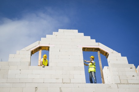Builders are working on the top of house construction の写真素材