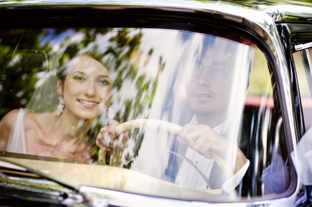The bride and groom have fun behind the wheel of retro carの写真素材