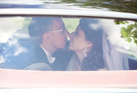 Beautiful happy young bride and groom kissing in retro carの写真素材