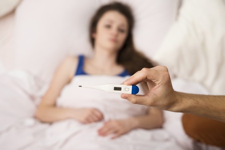 Sick woman is lying in bed  She has cold, flu and high fever 