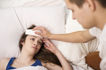 Sick woman is lying in bed  She has cold, flu and high fever の写真素材