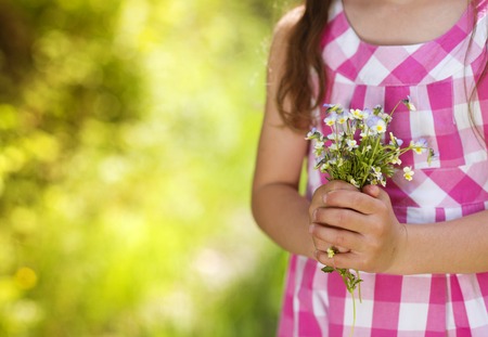 Detail of little girl with flower bouquet in the spring park の写真素材