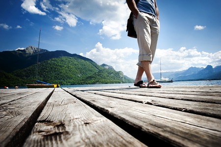 Close up of young man standing on the pier by the lakeの写真素材