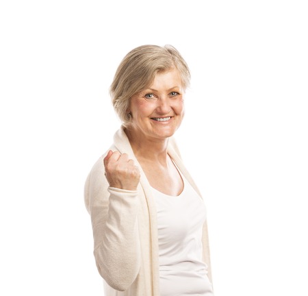 Portrait of a happy senior woman saying yes and gesturing while isolated on white background