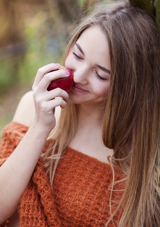 Outdoor portrait of beautiful girl holding an appleの写真素材