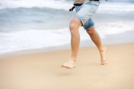 Detail of male feet running at the sandy beachの写真素材