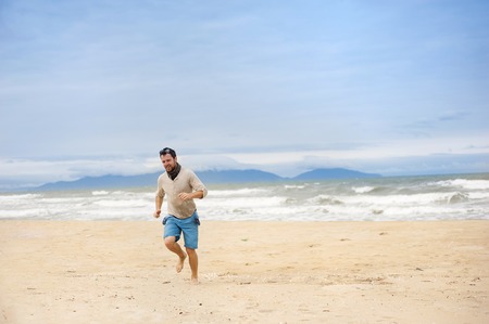 Handsome young Caucasian man walking alone with backpack on the beachの写真素材