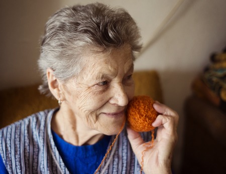 Portrait of senior woman sitting in armchair and knitting at homeの写真素材