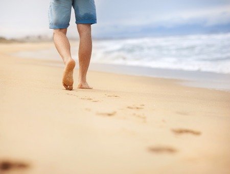 Detail of male feet walking at the sandy beachの写真素材