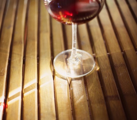 Detail of glass of red wine on woodden floorの写真素材