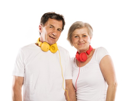 Senior couple listening to music with headphones, isolated on whiteの写真素材