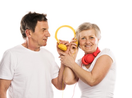 Senior couple listening to music with headphones, isolated on whiteの写真素材