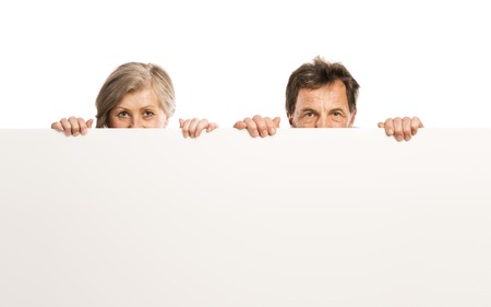 Portrait of happy senior couple with blank advertising board or copy space, isolated on whiteの写真素材