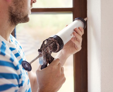 Man applying silicone sealant with caulking gunの写真素材