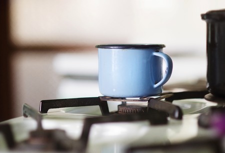 Old blue metal mug on gas cooker