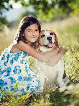 Cute little girl is playing with her dog in the green parkの写真素材