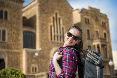 Pretty young female tourist with backpack in front of the church in Barcelona, Spain 