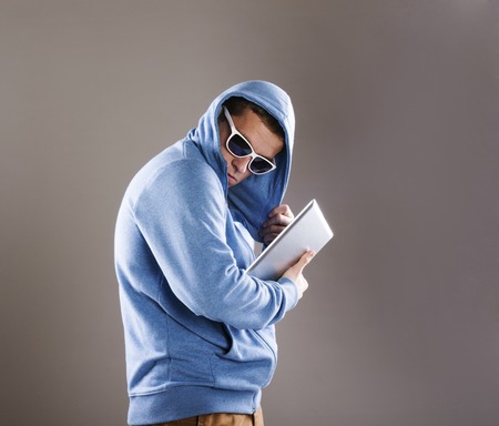 Dangerous man in mask with tablet on isolated backgroundの写真素材