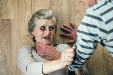 Woman victim of domestic violence and abuse  Mature woman with black eye scared of a man with a belt の写真素材