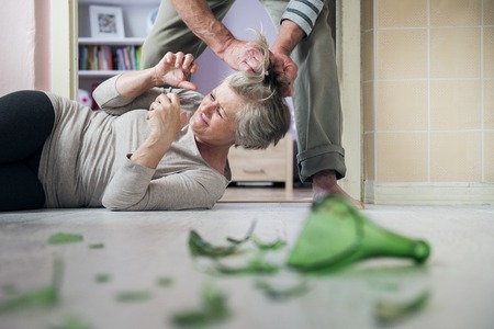 Woman victim of domestic violence and abuse  Mature woman scared of a man with broken bottleの写真素材