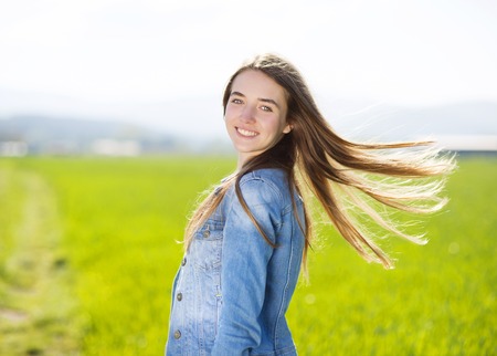 Happy young girl in blue jeans jacket enjoying free time in green fieldの写真素材