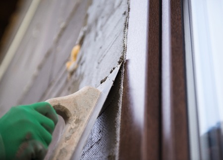Plasterer spreading out plaster with trowel around the windowsの写真素材