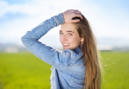 Happy young girl in blue jeans jacket enjoying free time in green fieldの写真素材