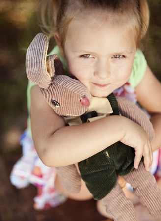 Outdoor portrait of cute little girl holding her toyの写真素材