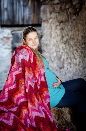 Outdoor portrait of beautiful pregnant woman holding her belly