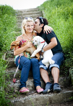 Happy young couple is playing their two dogs in green nature