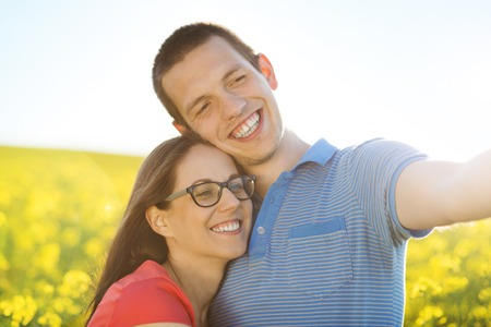 Happy young couple in love with heart shaped baloon in yellow colza fieldの写真素材