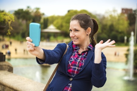 Pretty young female tourist taking selfie in front of the fountain in Barcelona, Spain 