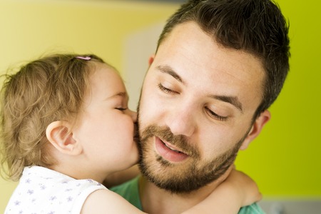 Indoor portrait of young father hugging his little daughterの写真素材