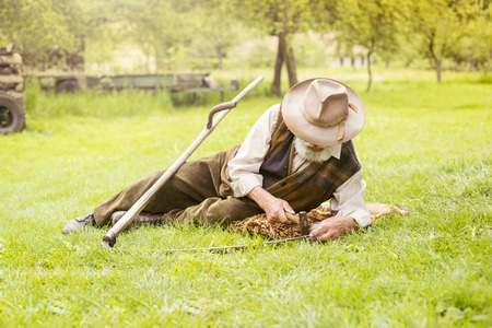 senior farmer using scythe to mow the lawn traditionallyの写真素材