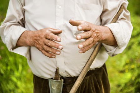 Old farmer with beard working with rake in gardenの写真素材