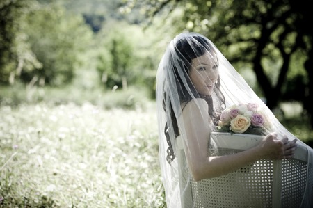 Bride in white wedding dress sitting on chair at the meadowの写真素材