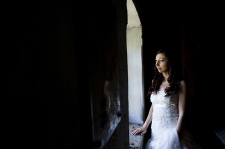 Lovely and happy brunette bride posing in old houseの写真素材