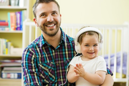 Portrait of happy father and his little daughter listening to music with headphonesの写真素材