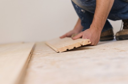 Handyman installing wooden floor in new houseの写真素材
