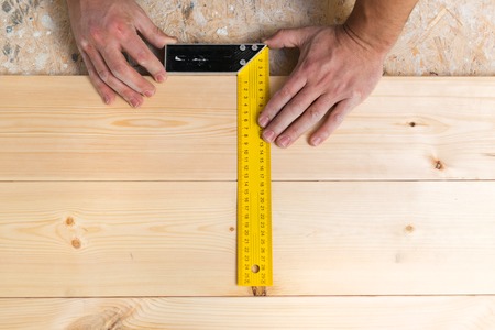Close up of male hands measuring wood flooringの写真素材