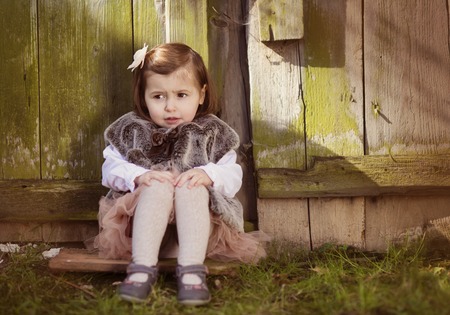 Outdoor portrait of cute little girl sitting on the old roof topの写真素材