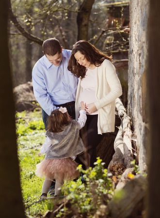 Happy pregnant family having fun in spring natureの写真素材
