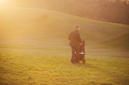 Happy young father with pram during the walk in natureの写真素材