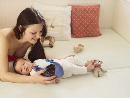 Young mother is playing with her little baby