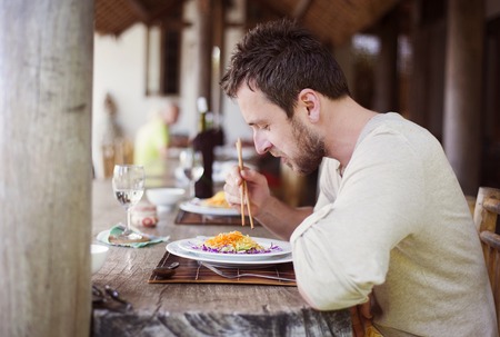 Man enjoying a meal with chopsticks in vietnamese restaurantの写真素材
