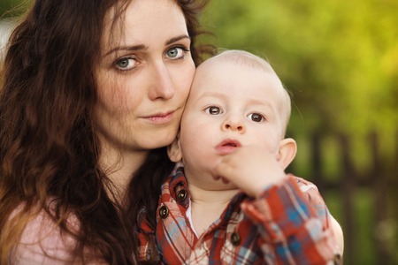 Portrait of a crying little boy who is being held by her mother, outdoorsの写真素材
