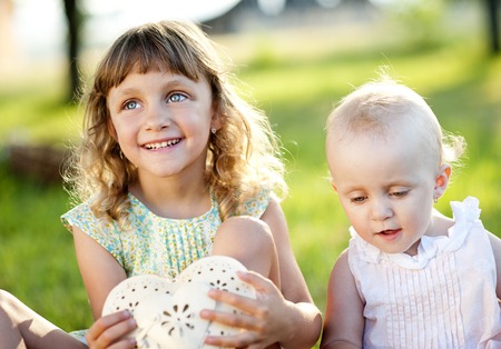 Two cute little sisters laughing and playing in green sunny parkの写真素材